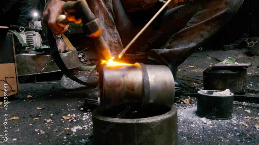 Closeup of a worker welding a seam on a steel cylinder in a metalworking shop. Fire and sparks fly from the electrode. Closeup of a worker welding a seam on a steel cylinder in a metalworking shop. Fire and sparks fly from the electrode.