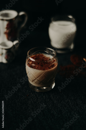 Irish cream liqueur in a glass with cinnamon on dark background