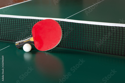 ping-pong racket and a ball on a green table. ping-pong net.