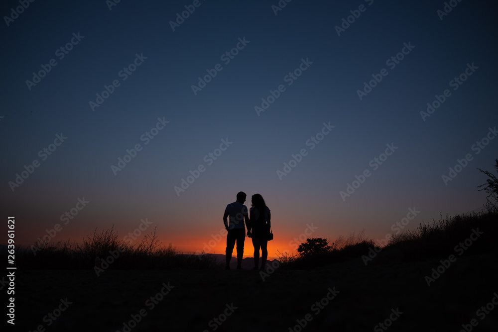 Silhouette of the couple against the sky at sunset.