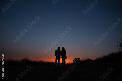 Silhouette of the couple against the sky at sunset.