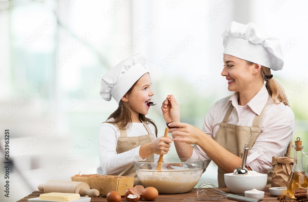 Portrait of adorable little girl and her mother baking together Portrait of adorable little girl and her mother baking together