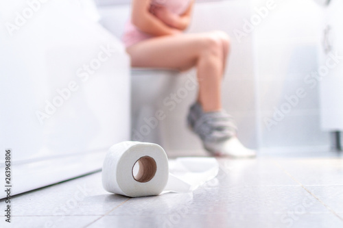 Ill, unwell woman suffering from diarrhea, constipation and cystitis at toilet. Stomach pain during PMS. Health care and pain concept photo