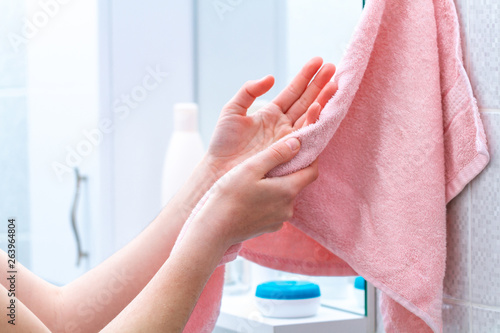 Person using towel for wiping hands dry after washing in bathroom at home. Hygiene and hand care