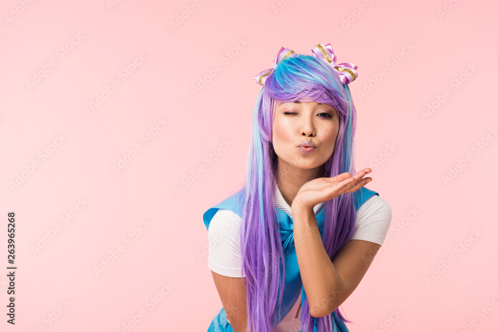 Asian anime girl sending air kiss and winking isolated on pink Asian anime girl sending air kiss and winking isolated on pink