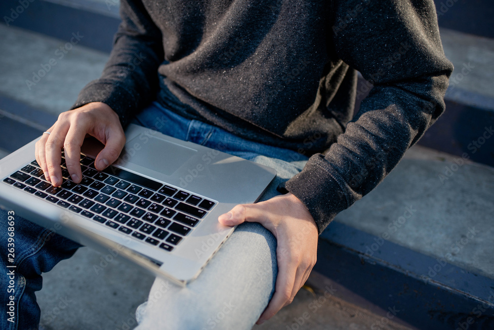 Remote job. A man with a laptop working outdoors. Freelancer workspace. Millennial and hipster. Concept for blogger, programmer, designer, manager. Modern Lifestyle. Online work on the Internet