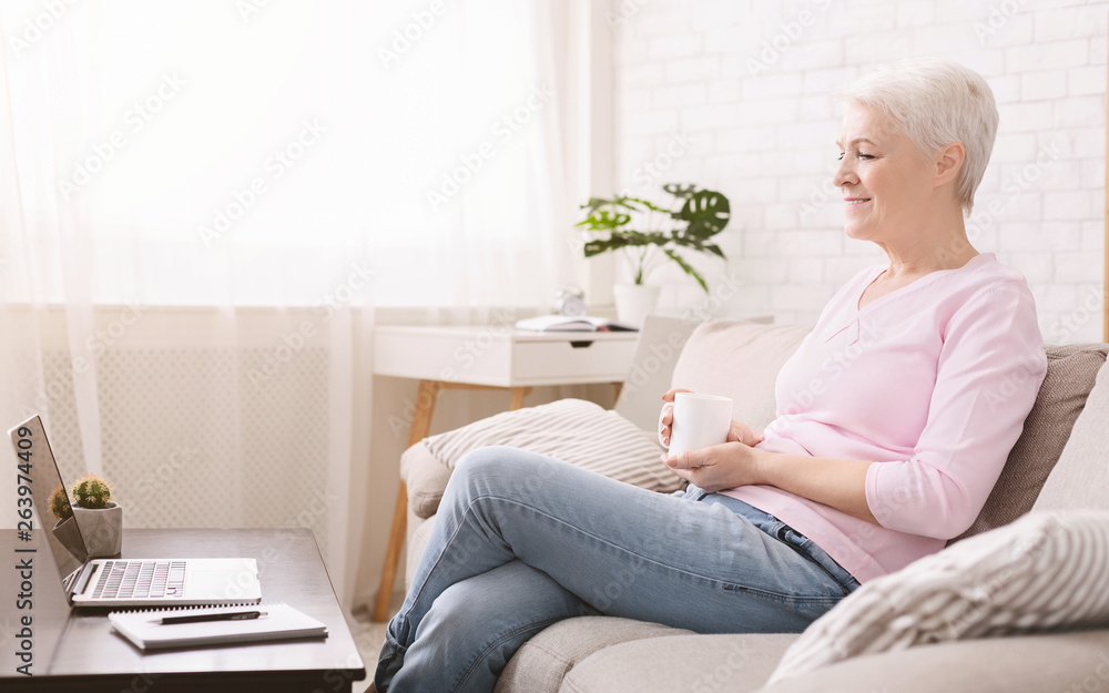 Positive modern senior woman watching video on laptop Positive modern senior woman watching video on laptop