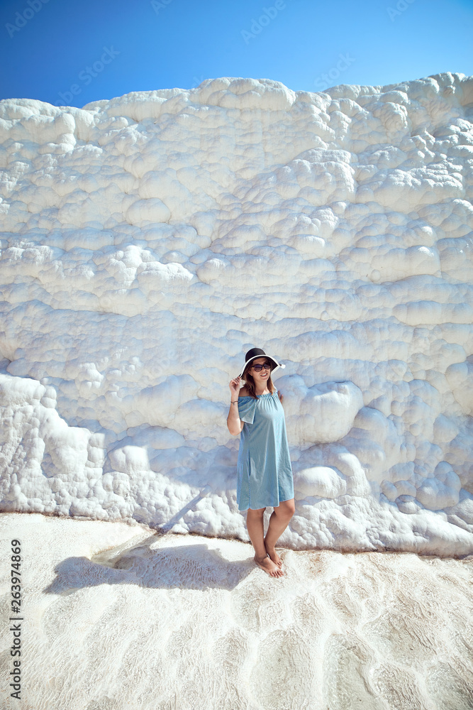 Young girl in hat looking on travertine pools and terraces in Pamukkale. Cotton castle in southwestern Turkey