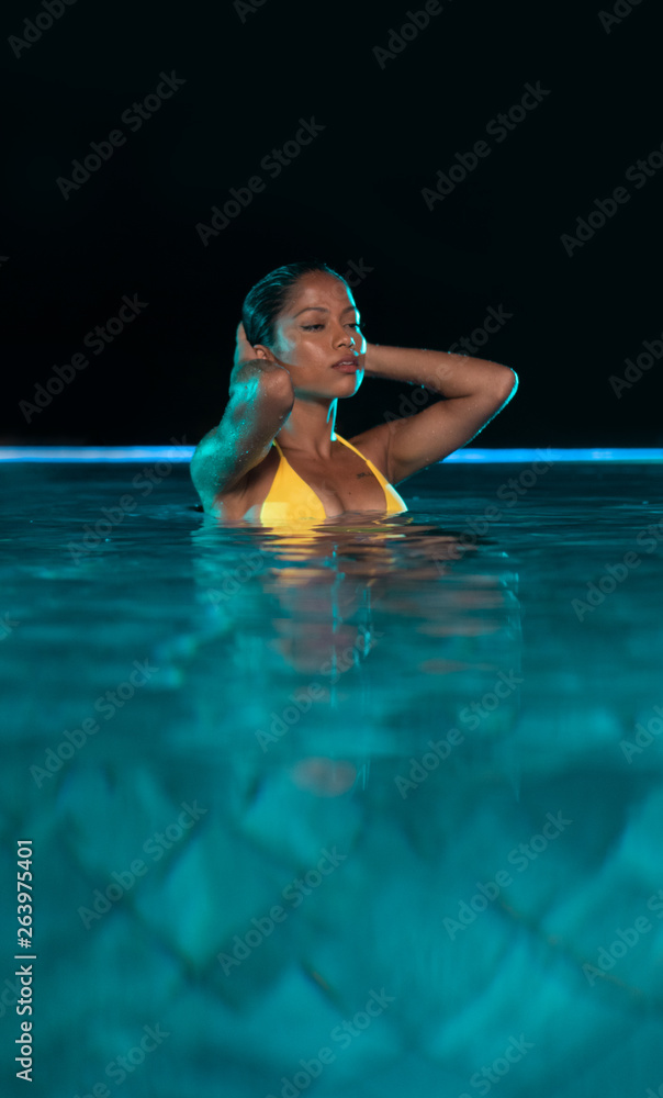Beautiful woman in yellow bikini relaxing in outdoor swimming pool during  night Stock Photo | Adobe Stock