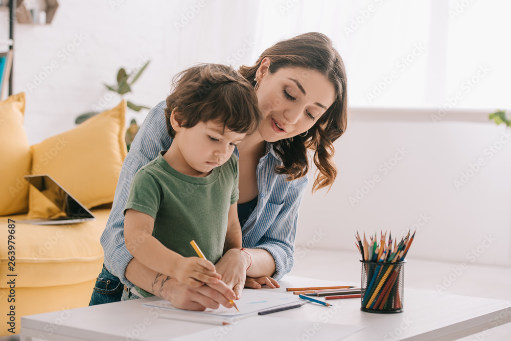 Mother and son drawing with color pencils in living room Mother and son drawing with color pencils in living room