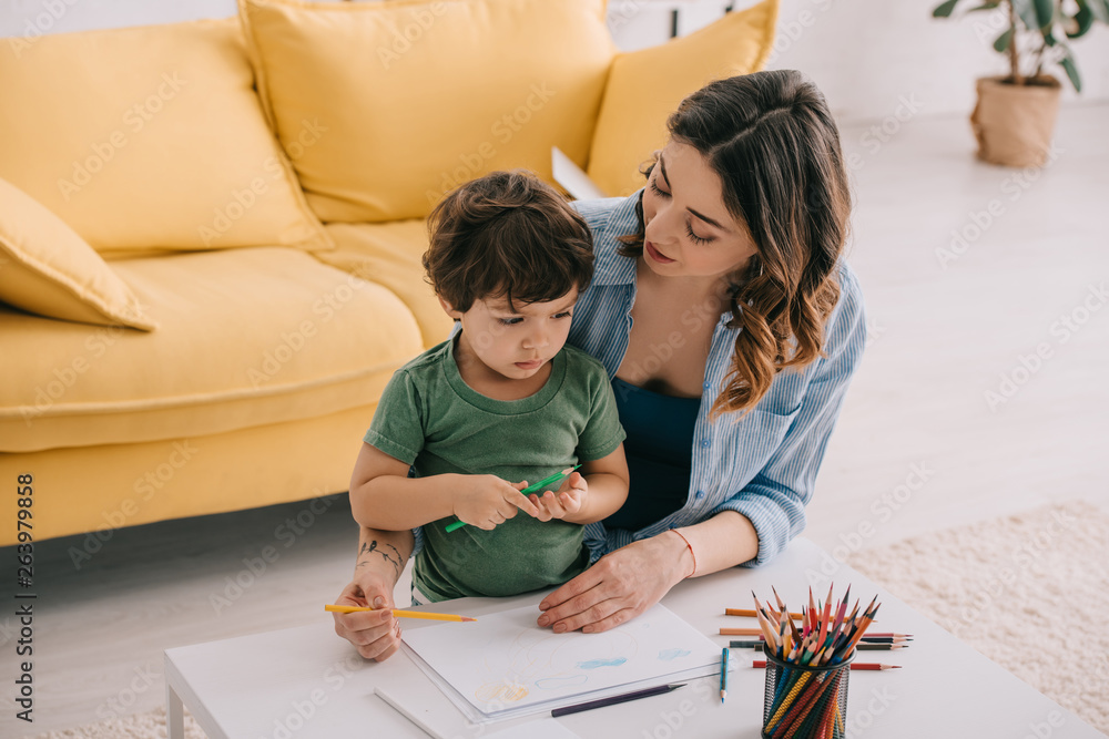 Mother and son drawing with color pencils in living room Mother and son drawing with color pencils in living room
