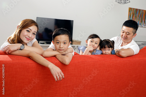 Parent mother father little child boy girl brother sister happy smile looking over the sofa