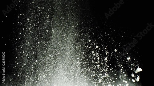 Explosion of white flour on black background. Stock footage. Explosion of thick cloud of white powder with crumbling particles on black isolated background