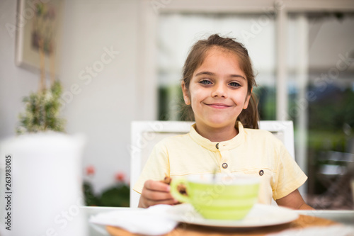 Portrait of smiling little girl having breakfast at home photo