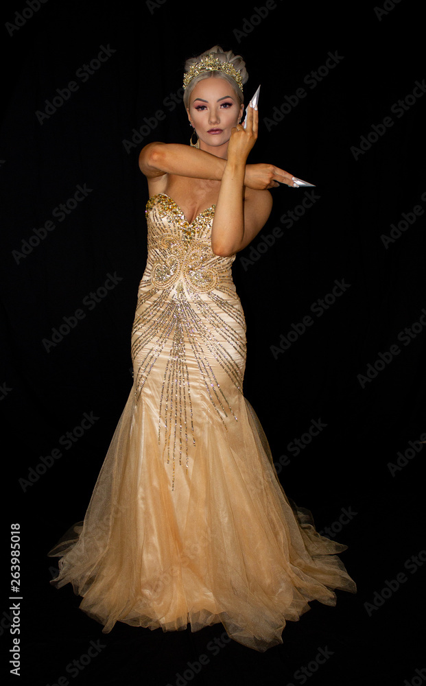 Fototapeta premium Golden goddess in crown, toying with knives