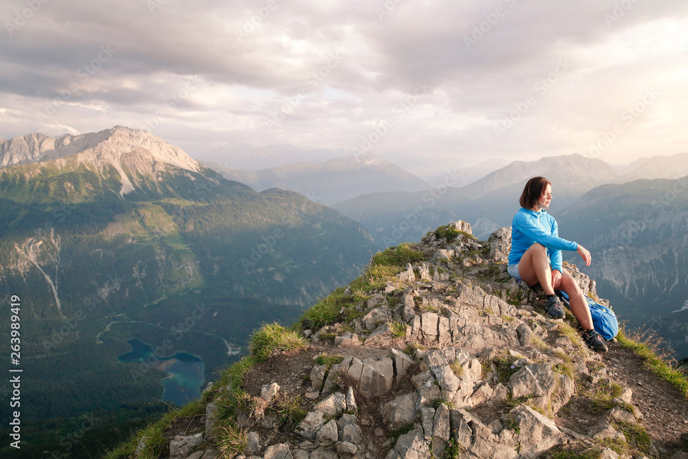 Austria, Tyrol, woman on a hiking trip in the mountains sitting on peak Austria, Tyrol, woman on a hiking trip in the mountains sitting on peak