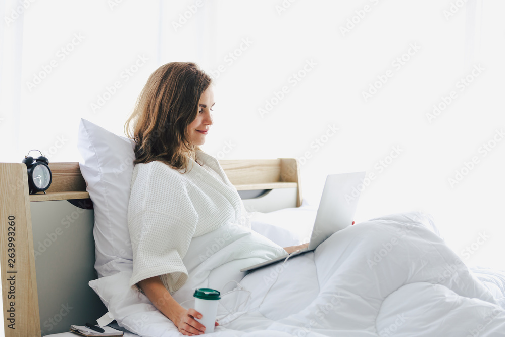 Woman typing work laptop on bed working in bedroom at home Woman typing work laptop on bed working in bedroom at home