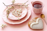 Close up of Branch of blossoming cherry, cup of tea, pearl necklace, gingerbread on pastel candy pink background