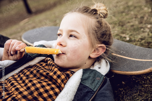 Little girl eating ice cream, resting head on skateboard photo