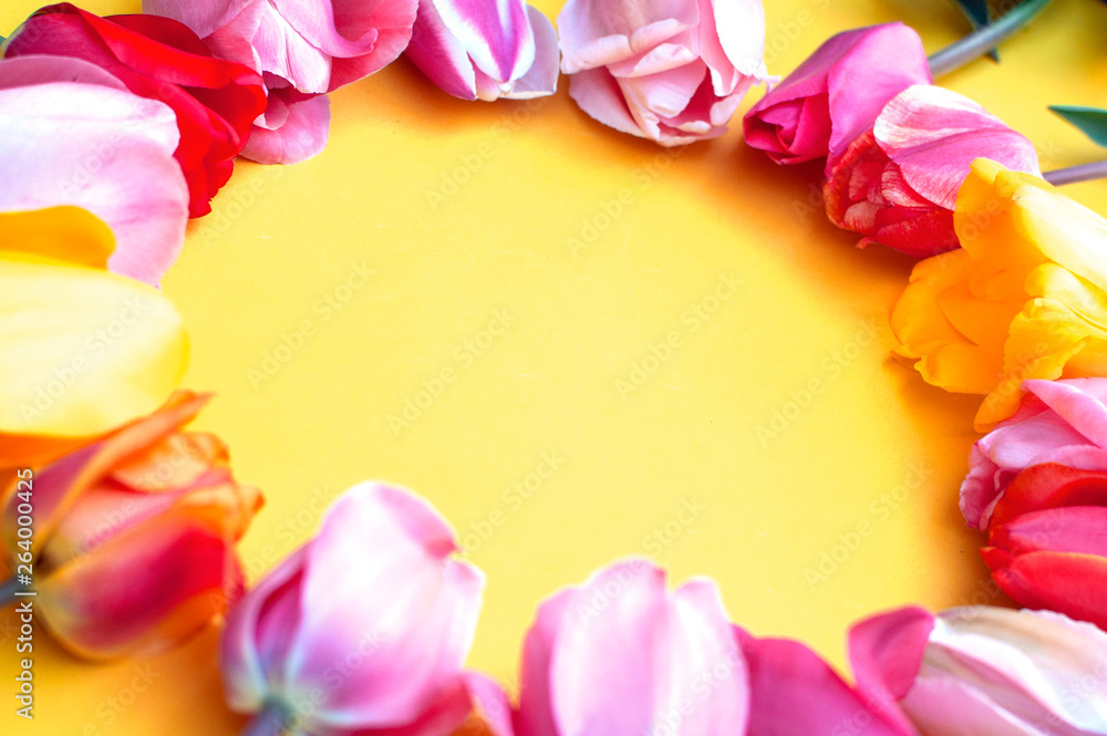 Round frame made of pink and yellow tulips, on a bright yellow background. Mother's day or Easter greeting card concept. Copy space for text