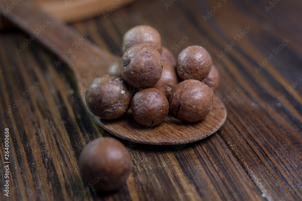 Macadamia nuts on the wooden spoon over the wooden table. Macadamia nuts on the wooden spoon over the wooden table.