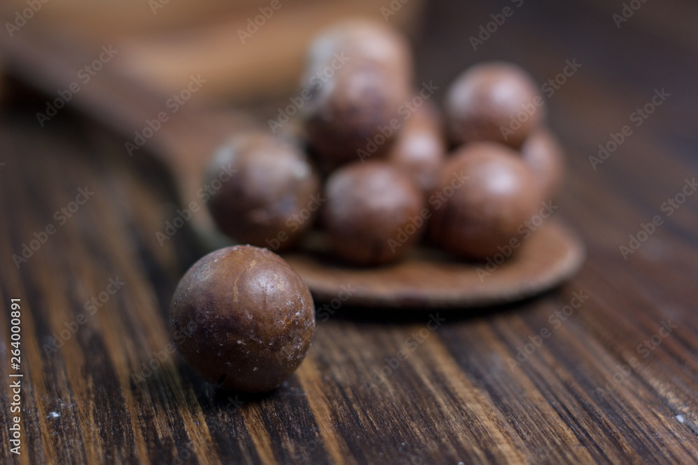 Macadamia nuts on the wooden spoon over the wooden table. Macadamia nuts on the wooden spoon over the wooden table.