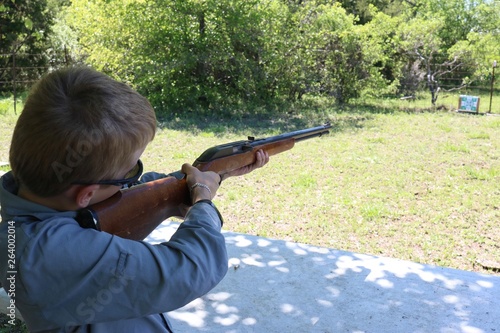 Young boy doing target practice with a rifle