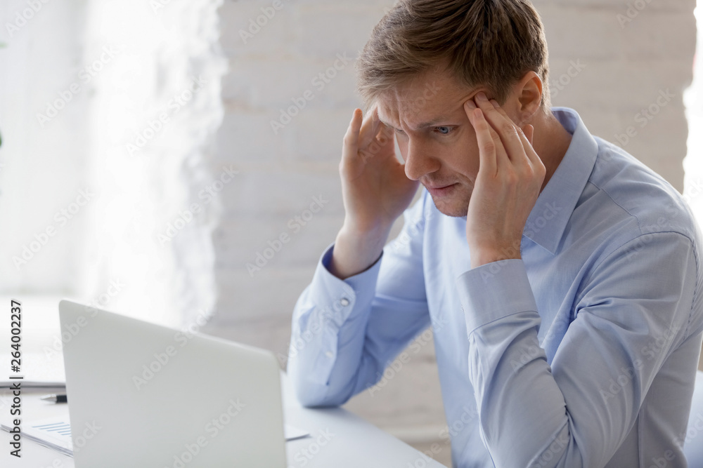 Man touching temples trying to focus having headache at work Man touching temples trying to focus having headache at work