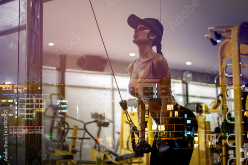 Asian woman with muscle pulling rope in the gym to exercise.