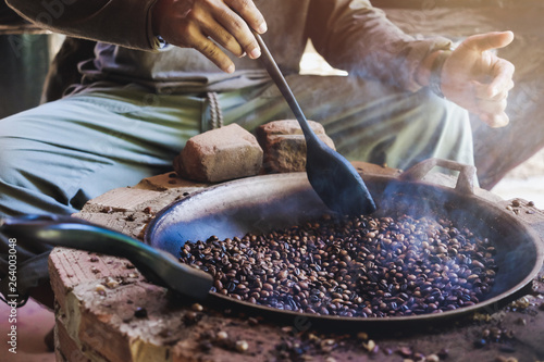 Canvastavla Asian men are sitting roasting coffee beans in a pan on an antique stove