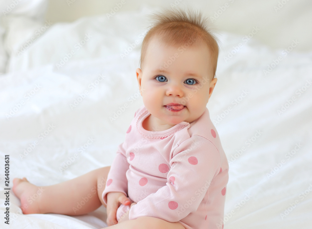 Charming girl 9 months on the bed in pink clothes Charming girl 9 months on the bed in pink clothes