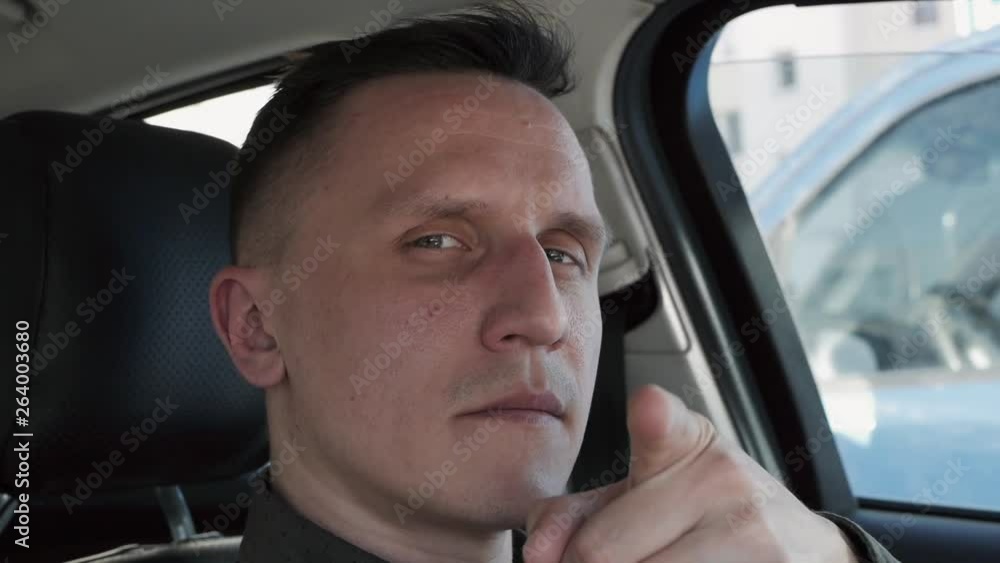 Portrait of a man sitting in a car. He points his finger directly at the camera Portrait of a man sitting in a car. He points his finger directly at the camera