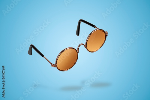 levitating round sunglasses over blue background, fashion accessory for summer