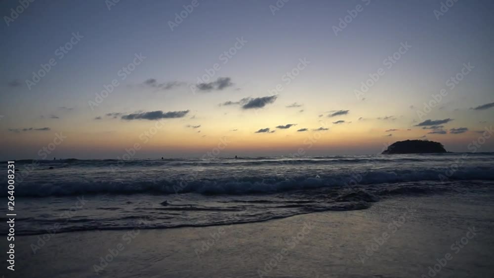 Beautiful sunset overlooking the sea and the horizon. The sound of waves can be heard, the island can be seen in the distance. Everything shimmers in yellow. The waves are gradually rolling.