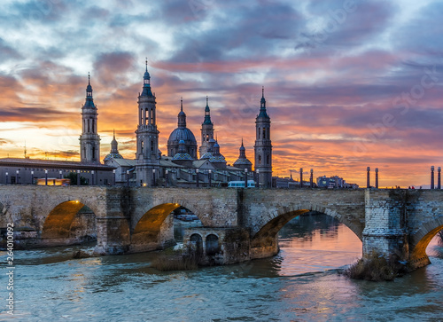 Vista de la Basílica del Pilar de Zaragoza con el río Ebro y l puente de piedra en una puesta de solel  photo