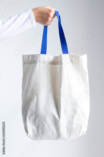 A hand holding a cotton shopping eco bag.