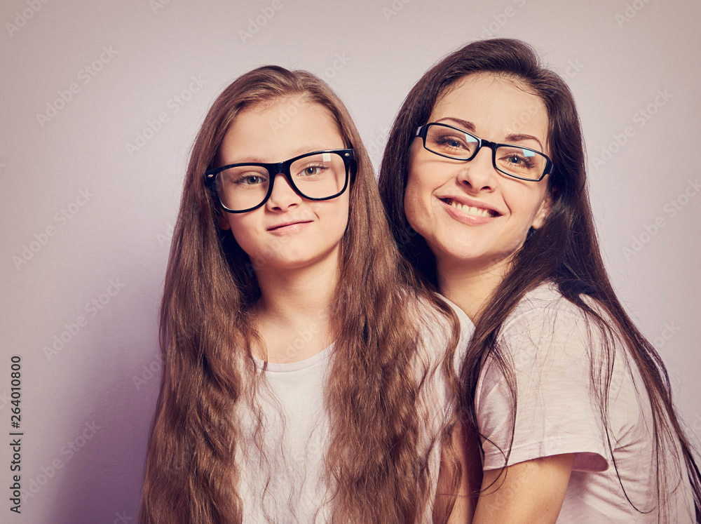 Happy young casual mother and smiling kid in fashion glasses hugging on purple background Happy young casual mother and smiling kid in fashion glasses hugging on purple background
