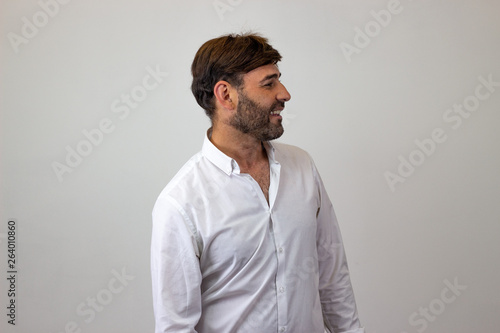 Fashion portrait of handsome young man with brown hair looking prideful, facing forwards and looking at the side. Isolated on white background.