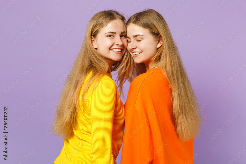 Side view of two smiling young blonde twins sisters girls in viv Side view of two smiling young blonde twins sisters girls in viv