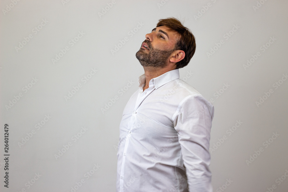 Obraz premium Fashion portrait of handsome young man with brown hair looking overwhelmed, facing forwards and looking at the horizon. Isolated on white background.