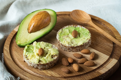 sandwich with avocado and almonds on a wooden brown background and linen towel
