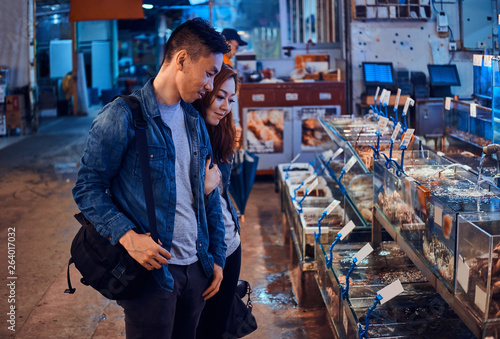 Canvas Print Romantic asian couple looking for something special at seafood chainese market