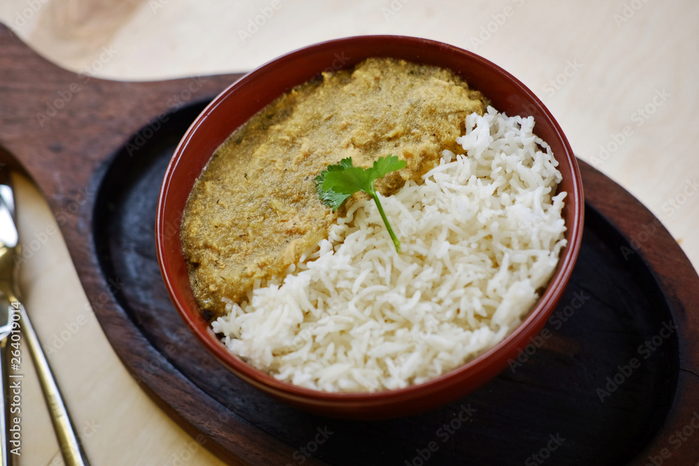 There are indian traditional curry dish with rice and coriander leaf on wooden tray. There are indian traditional curry dish with rice and coriander leaf on wooden tray.