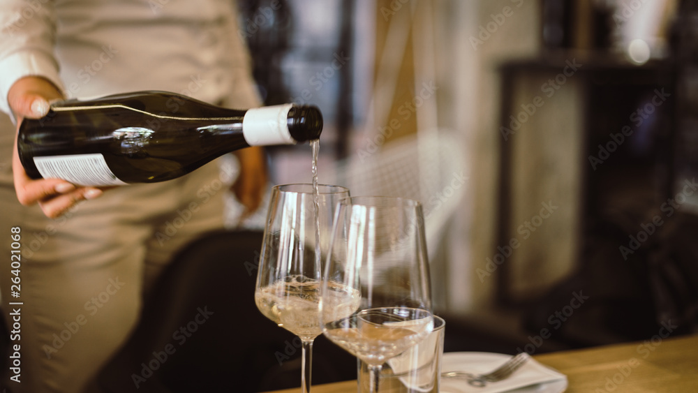 White wine pouring into glasses, close-up