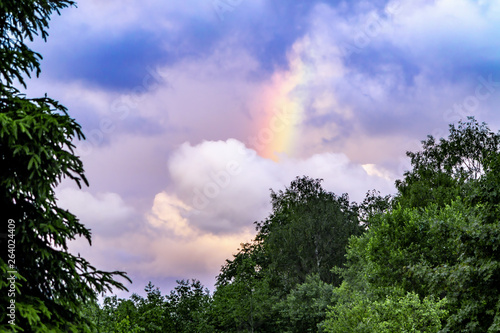 Rainbow after rain in a cloudy sky among dramatic clouds