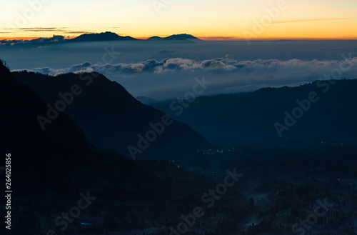 Peaceful atmosphere in early morning during sunrise over the shadow top mountain forest in mist.