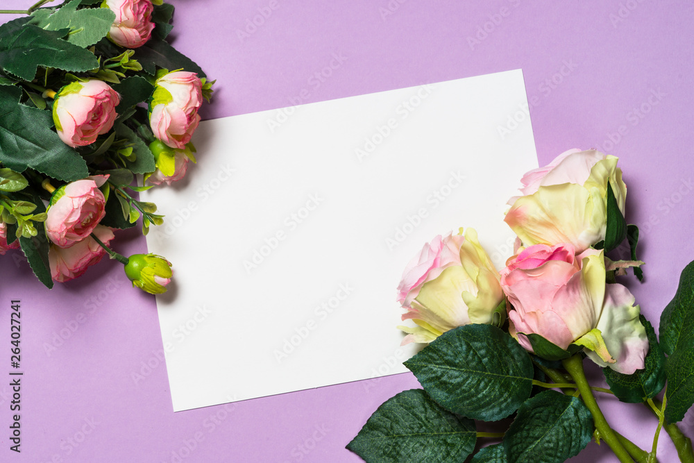 Empty paper sheet and flowers on a purple background. 