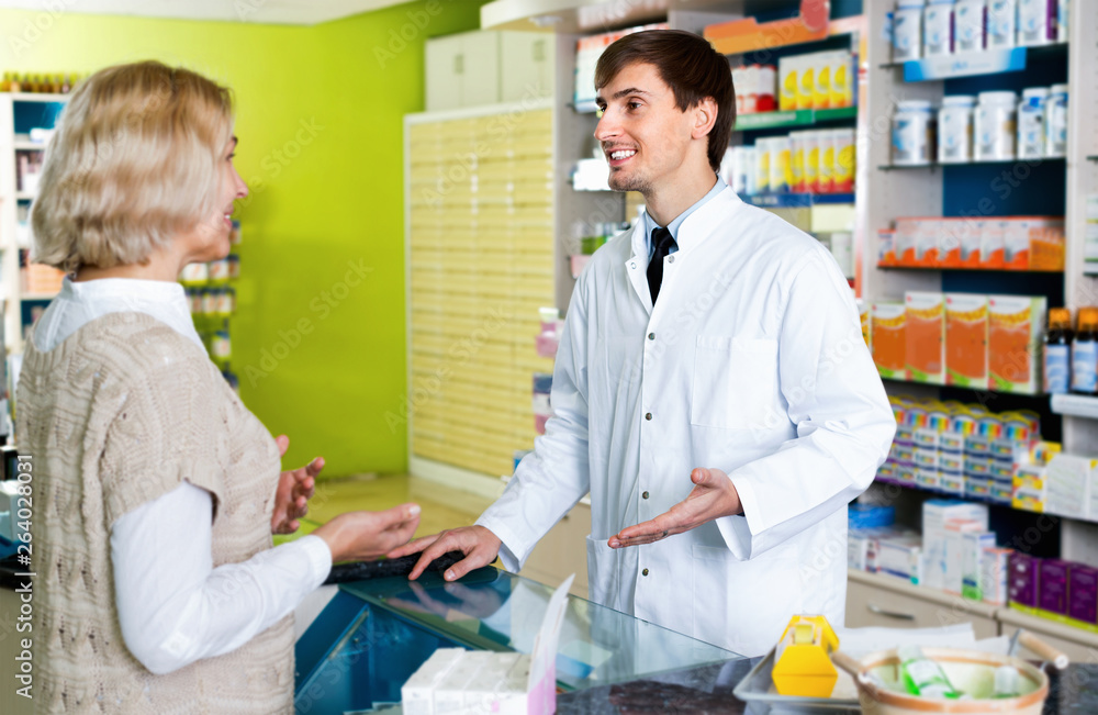 Smiling pharmacist counseling female customer