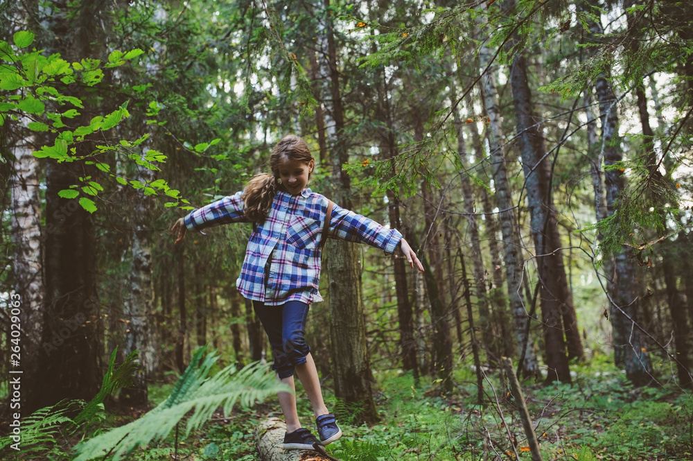 Obraz premium happy kid girl exploring summer forest, traveling on vacation. Teaching kids to love nature. Earth day concept.