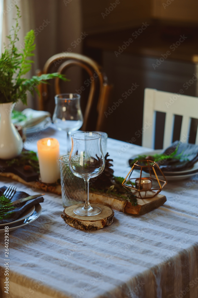 rustic country kitchen interior with festive table setting for summer dinner in natural green and brown tones. Small wooden cottage.